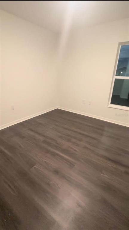 An empty room with white walls and dark wood-look flooring features a single window — 247 SUMMERLIN LOOP, HAINES CITY, FL
