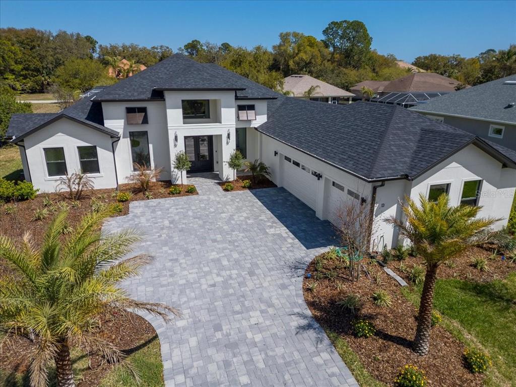 An aerial view of a modern white house with a dark roof and paver driveway — 13 OLD OAK DRIVE N, PALM COAST, FL