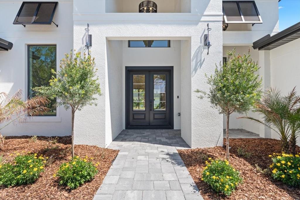 A paved walkway leads to the dark double front doors of a white stucco house — 13 OLD OAK DRIVE N, PALM COAST, FL