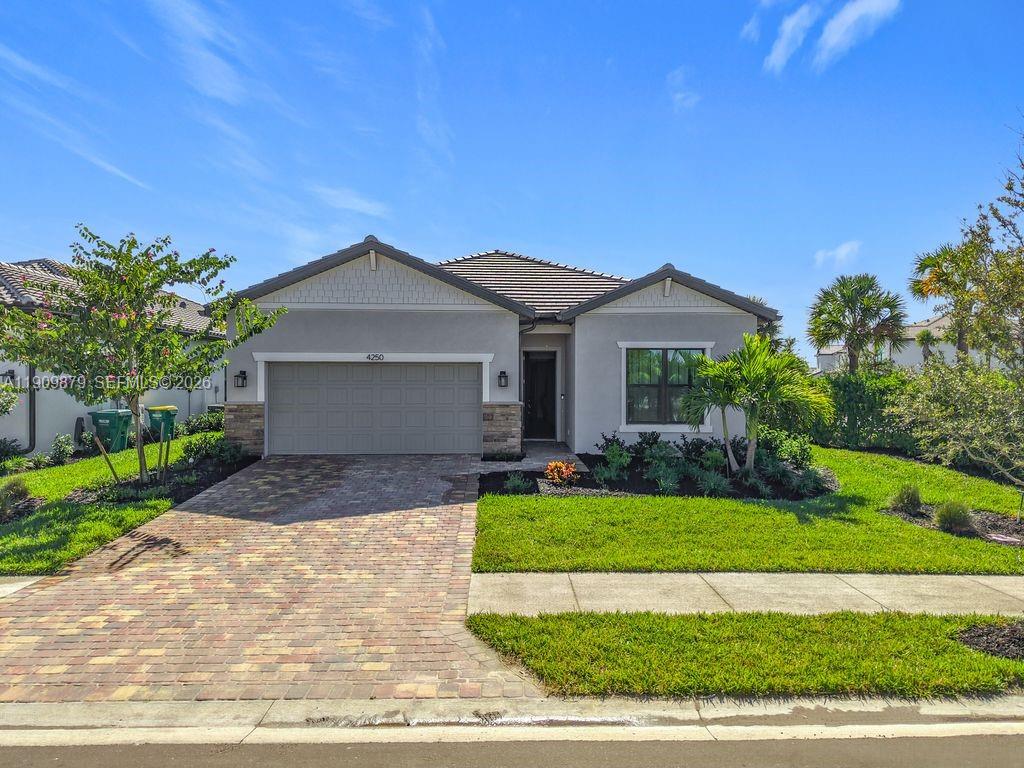 A single-story suburban house features a gray garage, stone accents, and a brick paver driveway — 4250 Annapolis Ave, Ave Maria FL 34142, AVE MARIA, FL