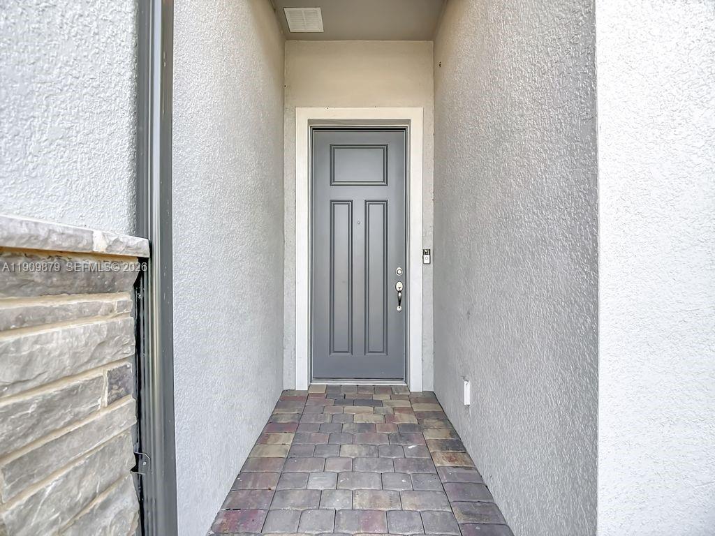 A gray front door is set within a recessed entryway with stone and stucco walls — 4250 Annapolis Ave, Ave Maria FL 34142, AVE MARIA, FL
