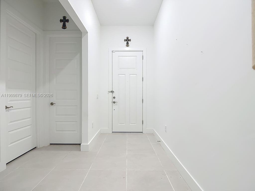 A white-walled entryway features light tile flooring, two closed doors, and two wall-mounted crosses — 4250 Annapolis Ave, Ave Maria FL 34142, AVE MARIA, FL
