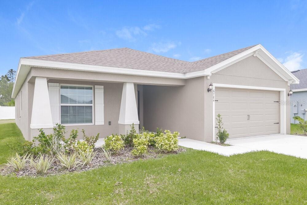 A single-story house with a beige exterior, a two-car garage, and a covered front porch — 6784 HANWORTH LANE, ZEPHYRHILLS, FL