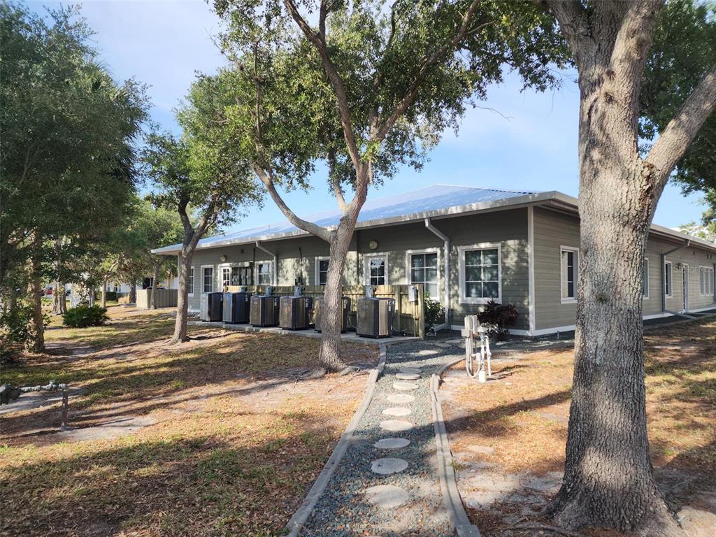 The exterior of a single-story building features light green siding, a metal roof, and AC units — 17801 MURDOCK CIRCLE UNIT C, PORT CHARLOTTE, FL