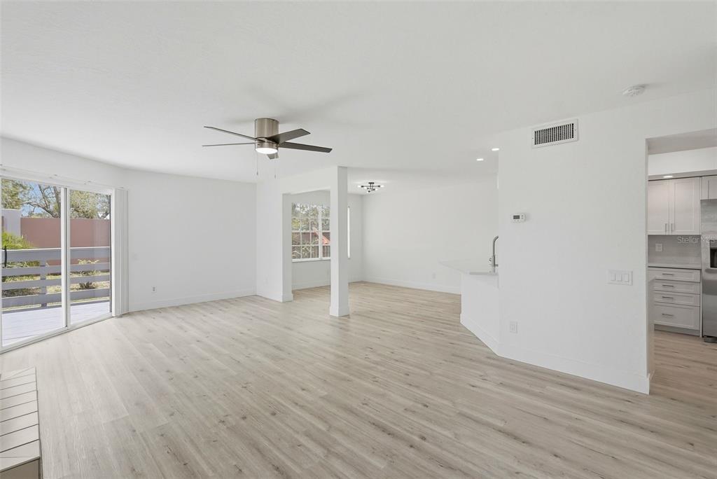 An open-concept living area with light wood-look flooring, a ceiling fan, and an adjacent kitchen — 14510 ALEJO COURT, SEMINOLE, FL