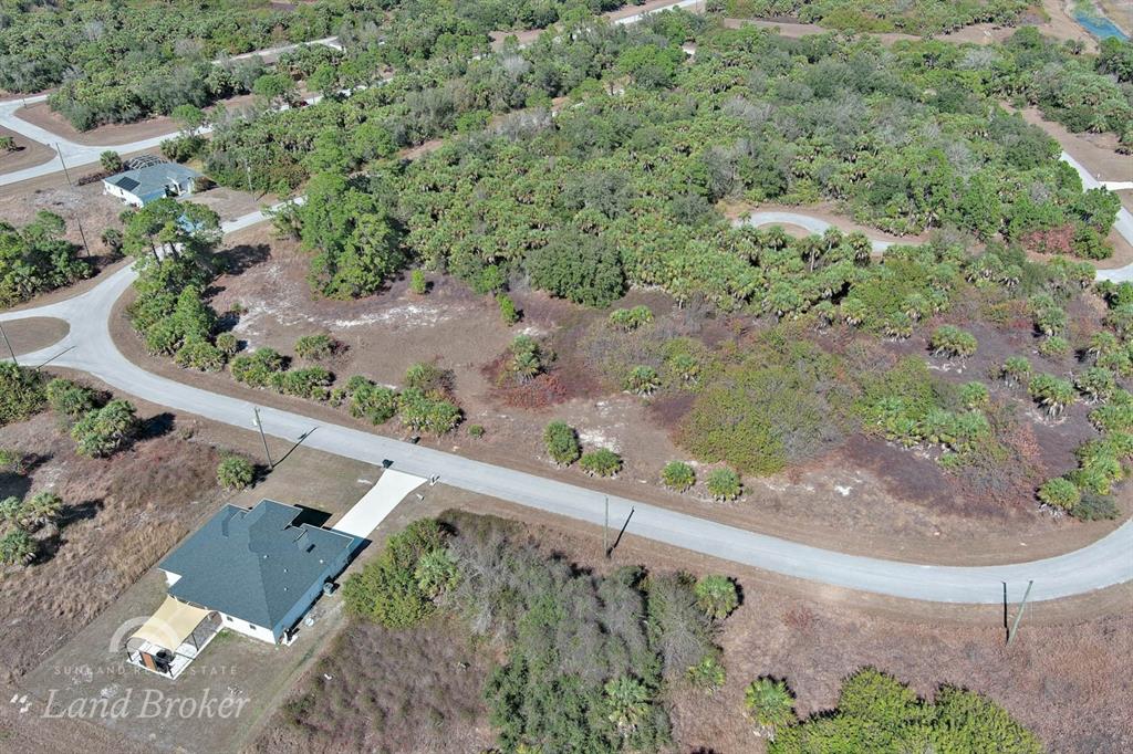 An aerial view shows a house and a large, wooded vacant lot with paved roads — EASTMAN CIRCLE, NORTH PORT, FL