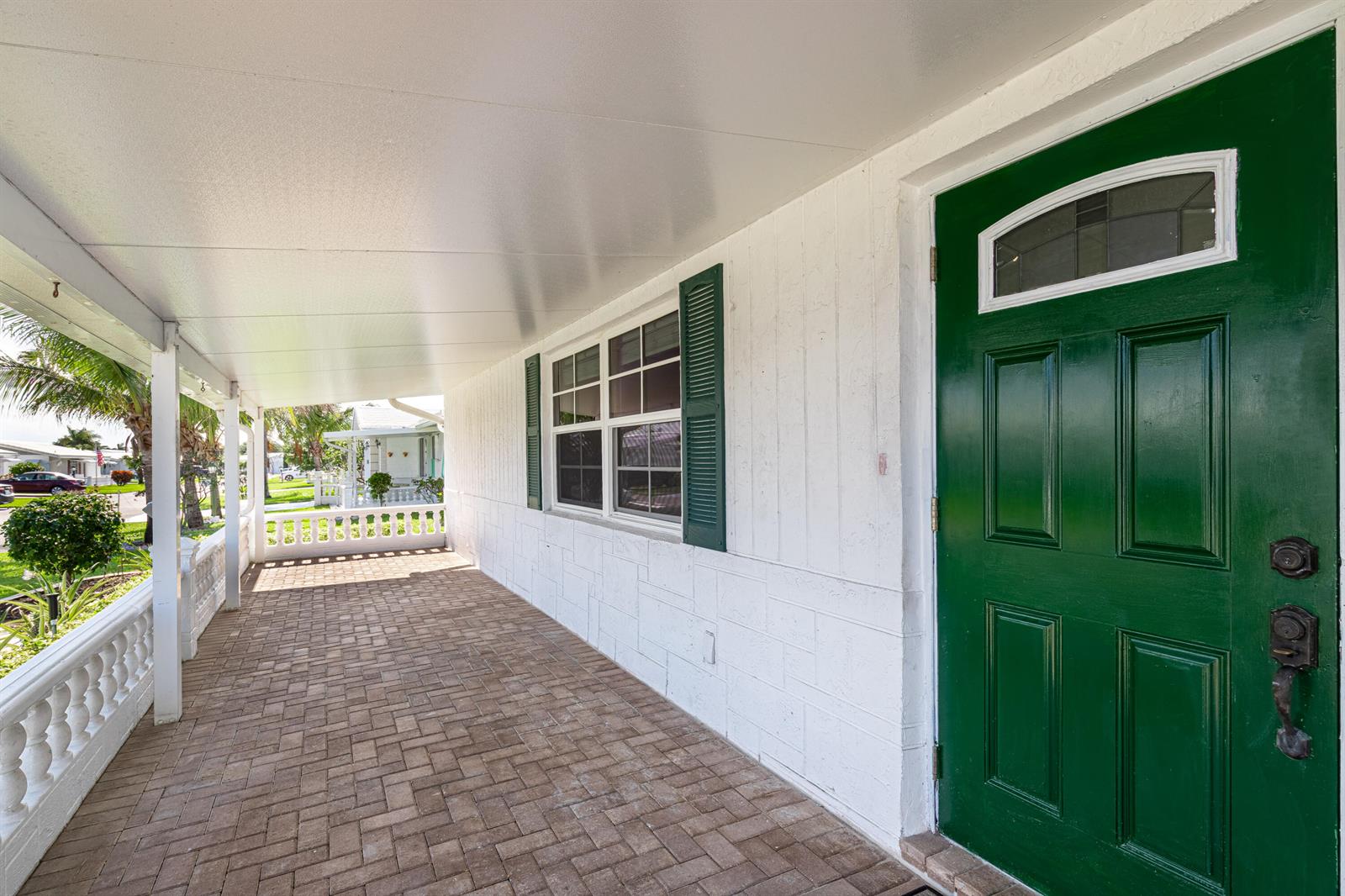 A covered porch with brick pavers, a white railing, and a green front door — 1907 SW 16th Avenue, Boynton Beach FL 33426, BOYNTON BEACH, FL