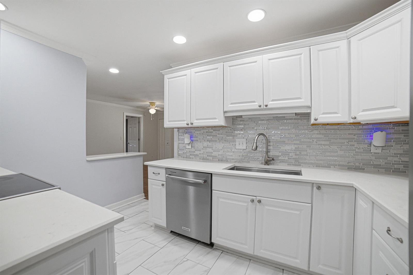 A kitchen features white cabinets, stainless steel appliances, a tiled backsplash, and light-colored countertops — 1907 SW 16th Avenue, Boynton Beach FL 33426, BOYNTON BEACH, FL