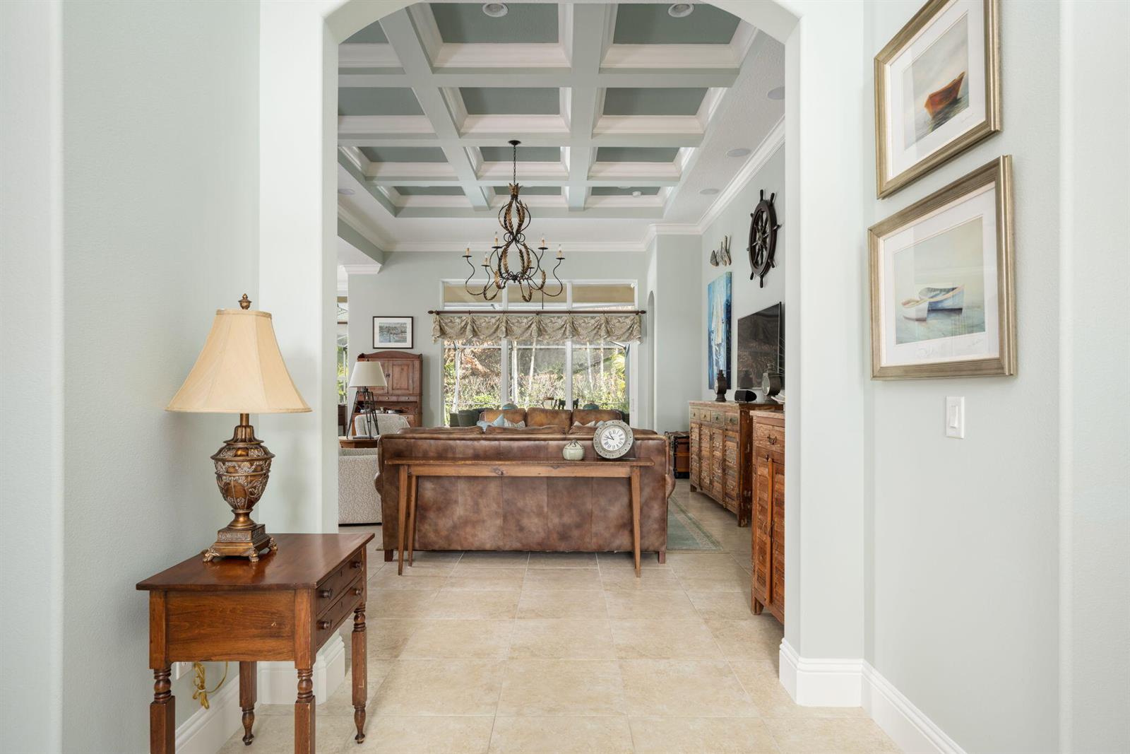 A view through an arched doorway into a living room with a coffered ceiling — 1101 River Wind Circle, Vero Beach FL 32967, VERO BEACH, FL
