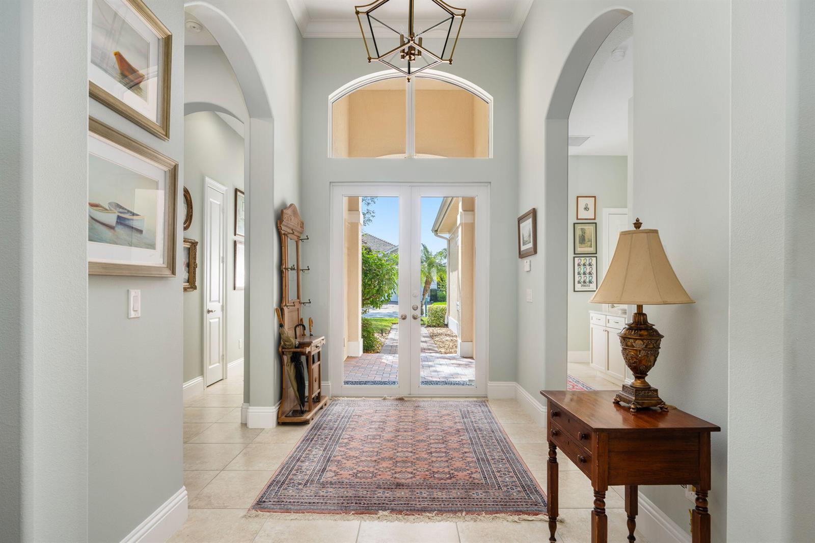 An entryway features a tile floor, a patterned rug, a wooden console table, and double doors — 1101 River Wind Circle, Vero Beach FL 32967, VERO BEACH, FL