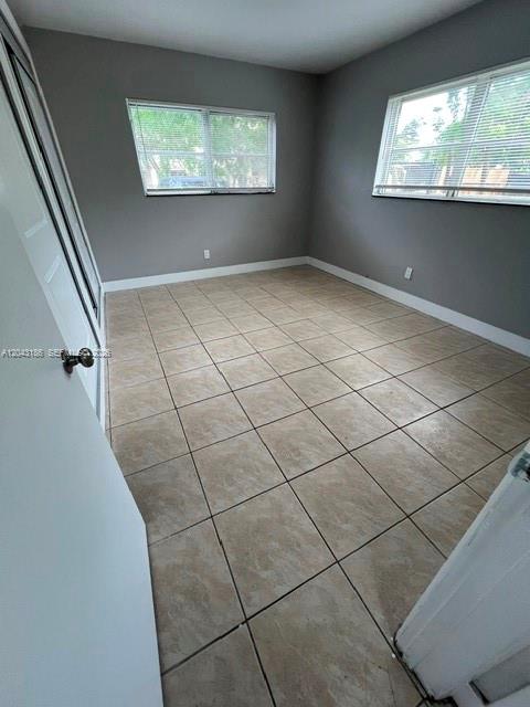 An empty bedroom features gray walls, light-colored tile flooring, and two windows with blinds — FORT LAUDERDALE, FL