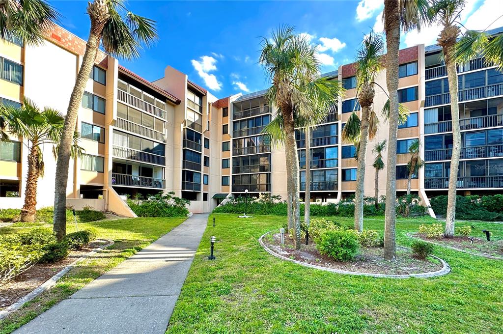 A multi-story apartment building with balconies and palm trees in a landscaped courtyard — 3006 CARING WAY UNIT 529, PORT CHARLOTTE, FL