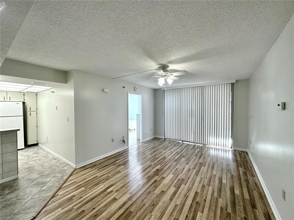 An open living area features wood-look flooring, a ceiling fan, and sliding glass patio doors — 3006 CARING WAY UNIT 529, PORT CHARLOTTE, FL