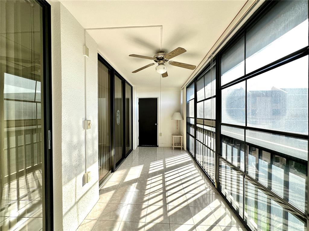 A sunroom with tiled floors, a ceiling fan, and large windows overlooking an exterior view — 3006 CARING WAY UNIT 529, PORT CHARLOTTE, FL