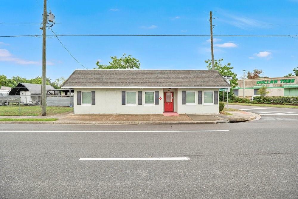 A single-story commercial building with a red door sits along a paved road — 3101 N ORANGE BLOSSOM TRAIL, ZELLWOOD, FL
