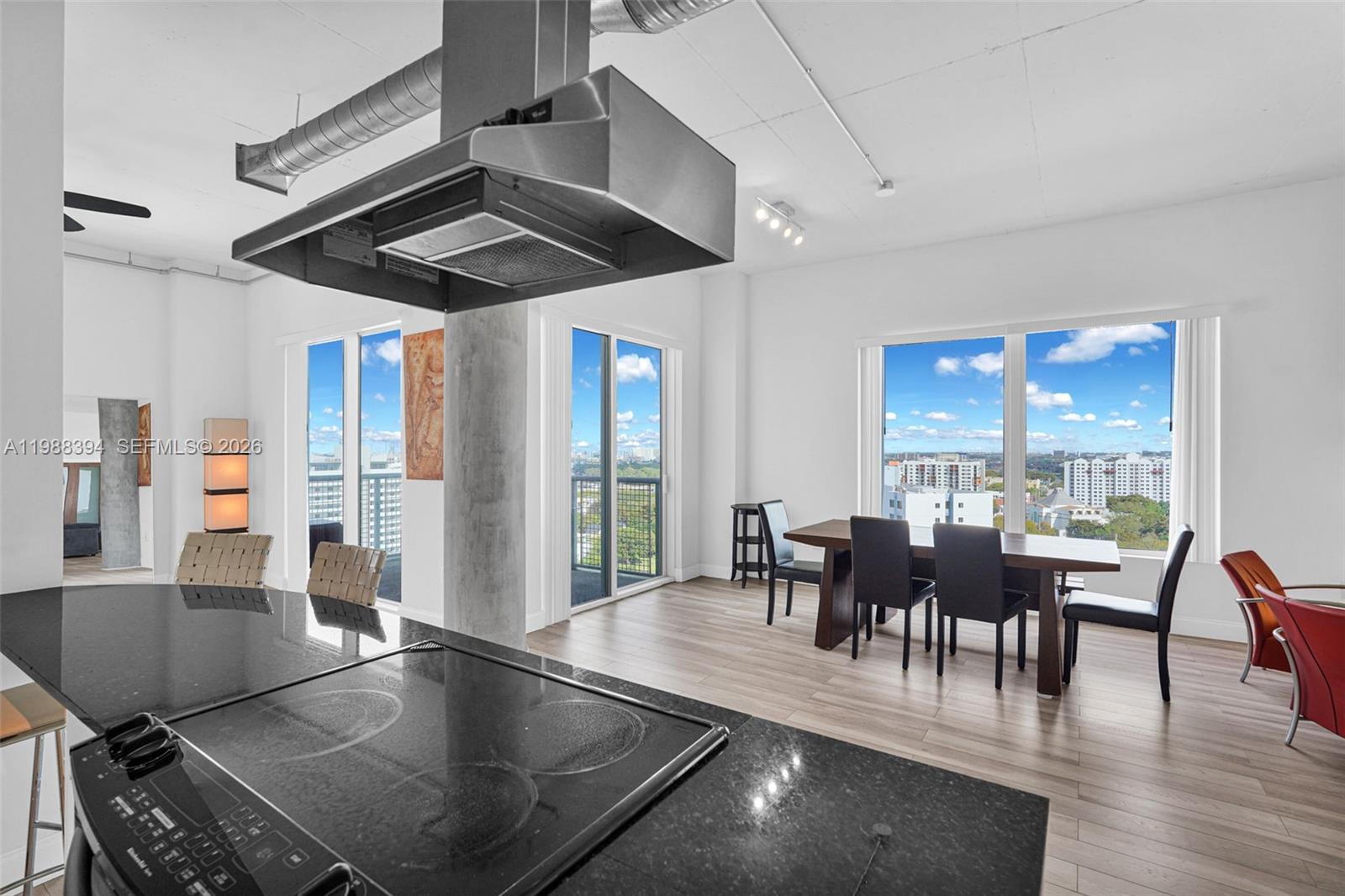 A modern kitchen and dining area features a black countertop, stainless hood, and city views — 10 SW South River Dr # 1615, Miami FL 33130, MIAMI, FL