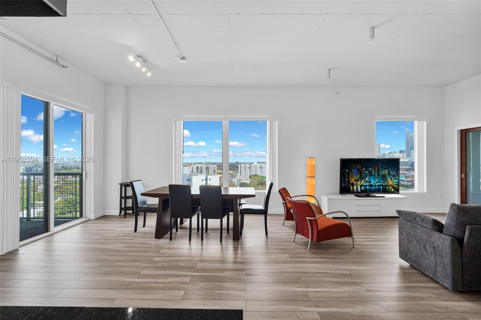 A modern living and dining area features light wood flooring, floor-to-ceiling windows, and city views — 10 SW South River Dr # 1615, Miami FL 33130, MIAMI, FL