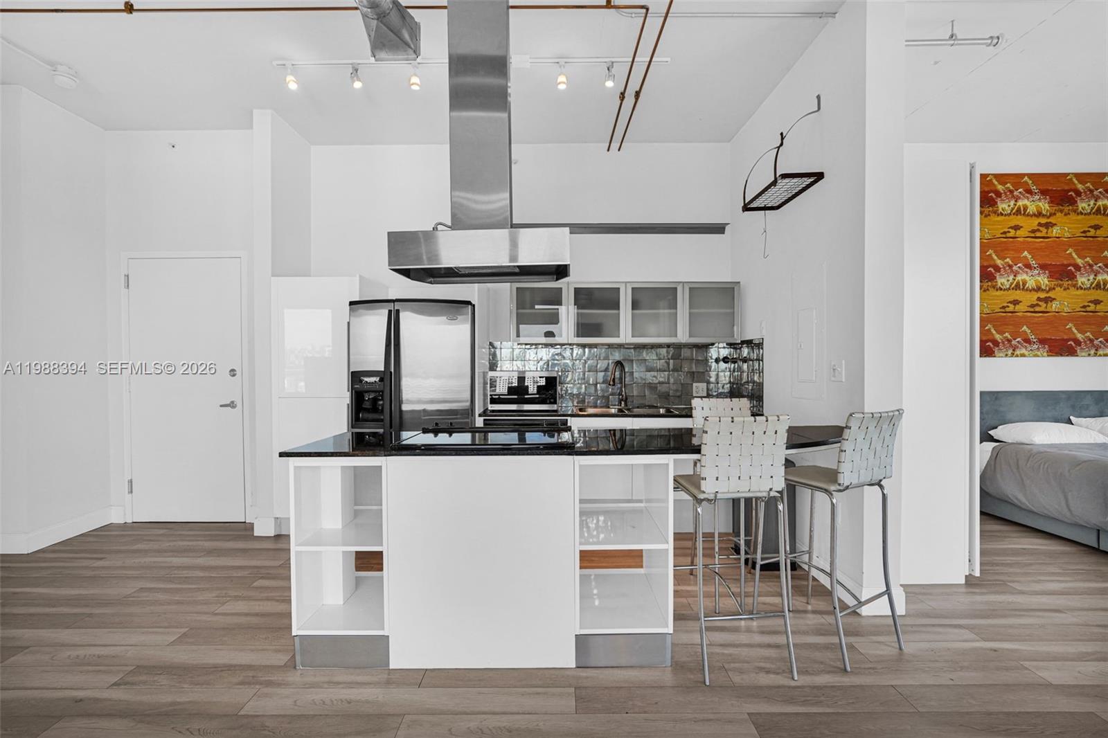 A modern kitchen features a black island, stainless steel appliances, and white cabinetry — 10 SW South River Dr # 1615, Miami FL 33130, MIAMI, FL