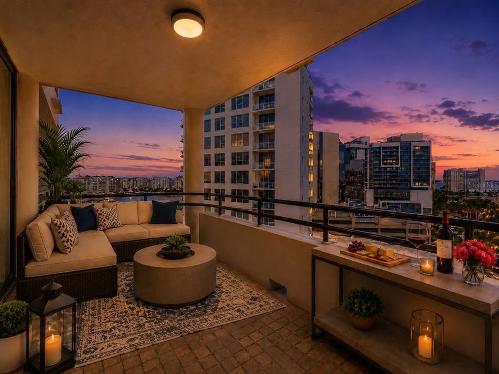 A furnished balcony features a sectional sofa, a round coffee table, and city skyline views — 1255 N GULFSTREAM AVENUE UNIT 1101, SARASOTA, FL