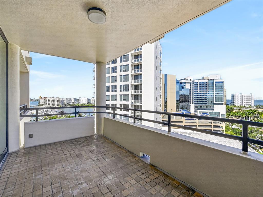 A balcony with tiled flooring overlooks a city skyline and a marina — 1255 N GULFSTREAM AVENUE UNIT 1101, SARASOTA, FL