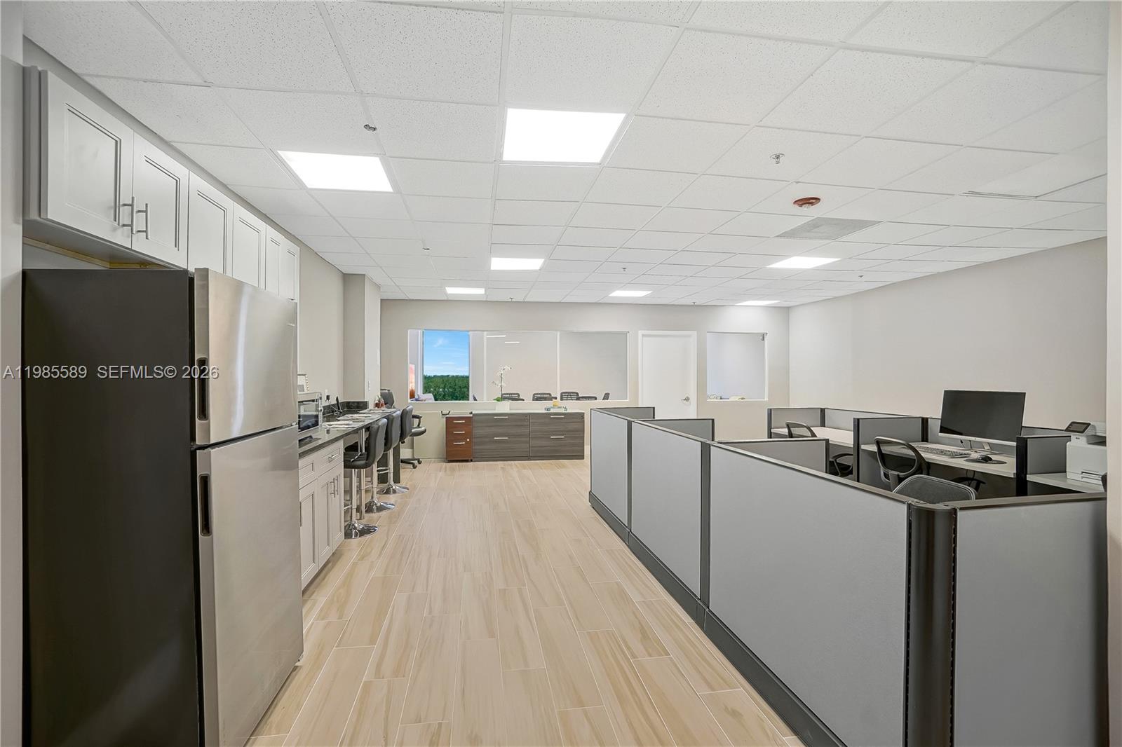 An office space features a kitchenette with stainless steel appliances, cubicles, and wood-look flooring — 12550 Biscayne Blvd # 902, North Miami FL 33181, NORTH MIAMI, FL