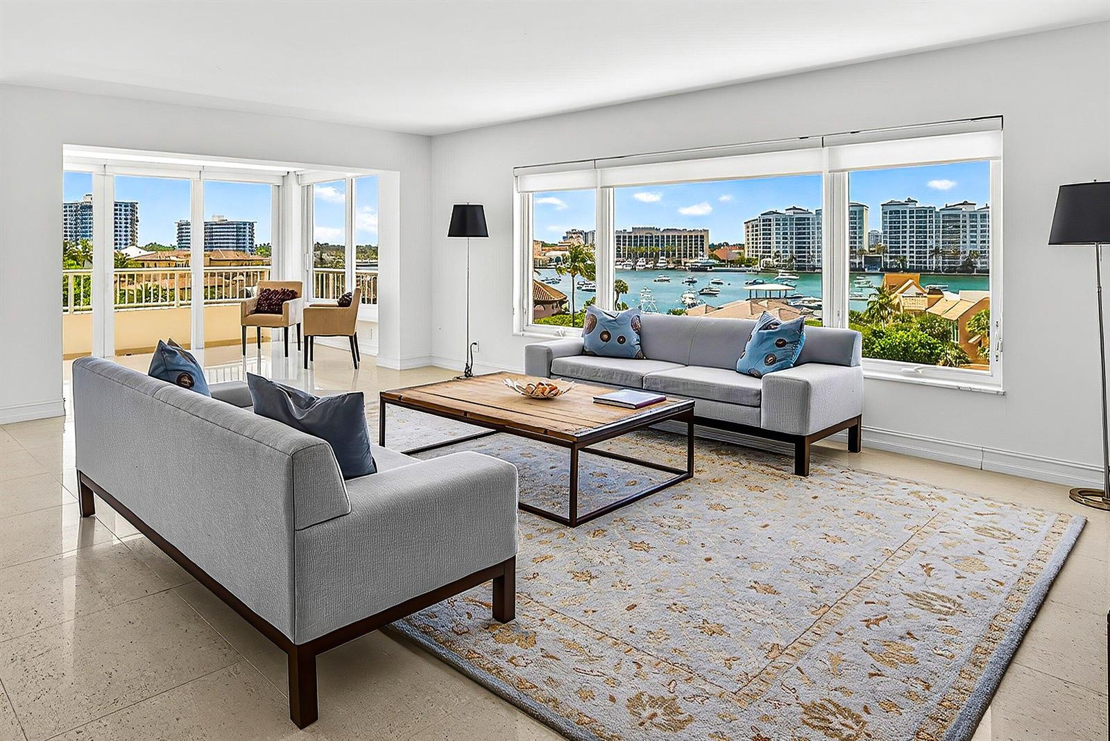 A living room with two gray sofas, a wooden coffee table, and large waterfront windows — 600 S Ocean Boulevard # 504, Boca Raton FL 33432, BOCA RATON, FL