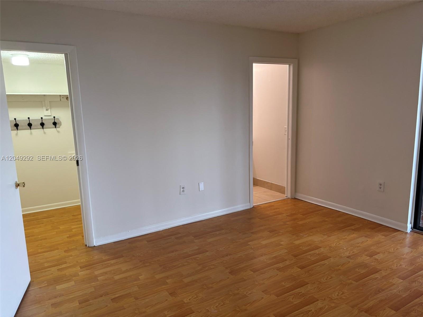 An empty room features wood-look flooring, two doorways, and beige walls — 8500 SW 133rd Ave Rd # 422, Miami FL 33183, MIAMI, FL