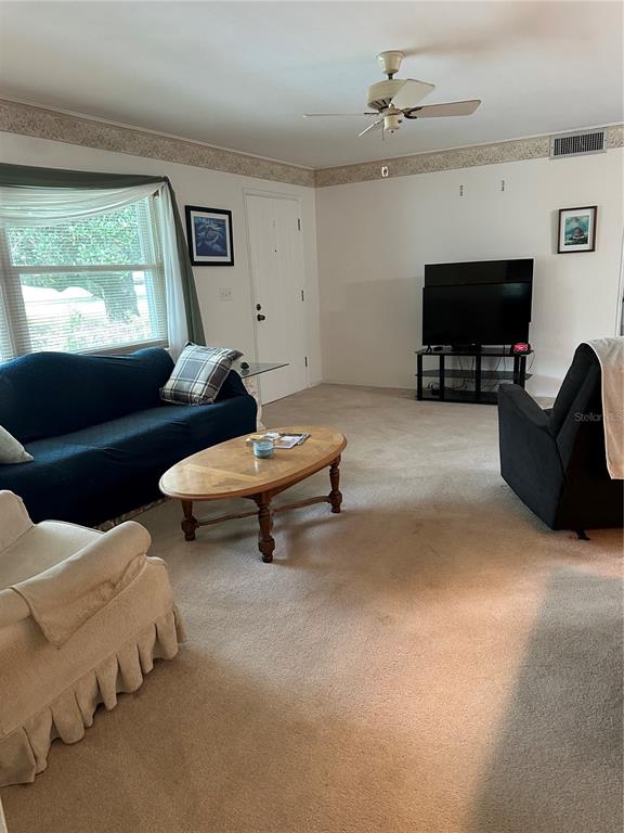 A living room features a dark sofa, a beige armchair, a coffee table, and a television — 3 S FILLMORE STREET, BEVERLY HILLS, FL