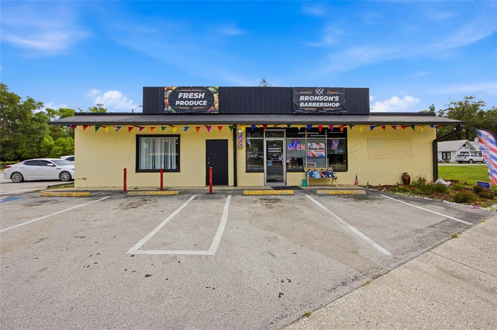 A yellow brick commercial building with a barbershop and produce store under a metal roof — 380 E HATHAWAY AVENUE, BRONSON, FL