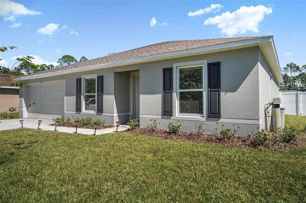 A single-story house with a gray stucco exterior, dark shutters, and a two-car garage — 38 PRETORIA LANE, PALM COAST, FL