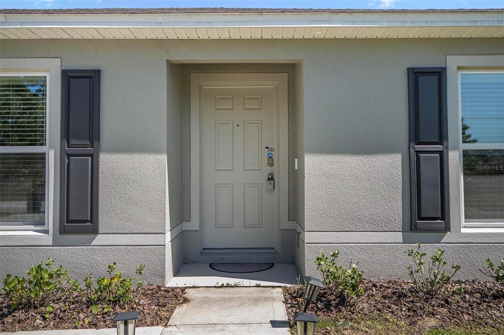 The exterior of a house features a white front door flanked by dark shutters — 38 PRETORIA LANE, PALM COAST, FL