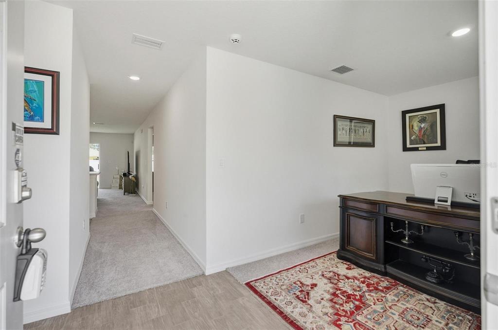 An entryway leads to a carpeted hallway and an office space with a wooden desk — 38 PRETORIA LANE, PALM COAST, FL