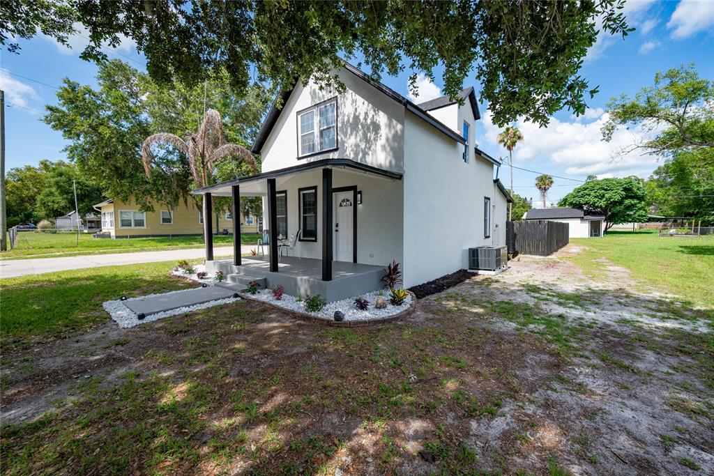 A white two-story house with a black-trimmed porch and roof stands on a grassy lot — 922 DELAWARE AVENUE, ST CLOUD, FL