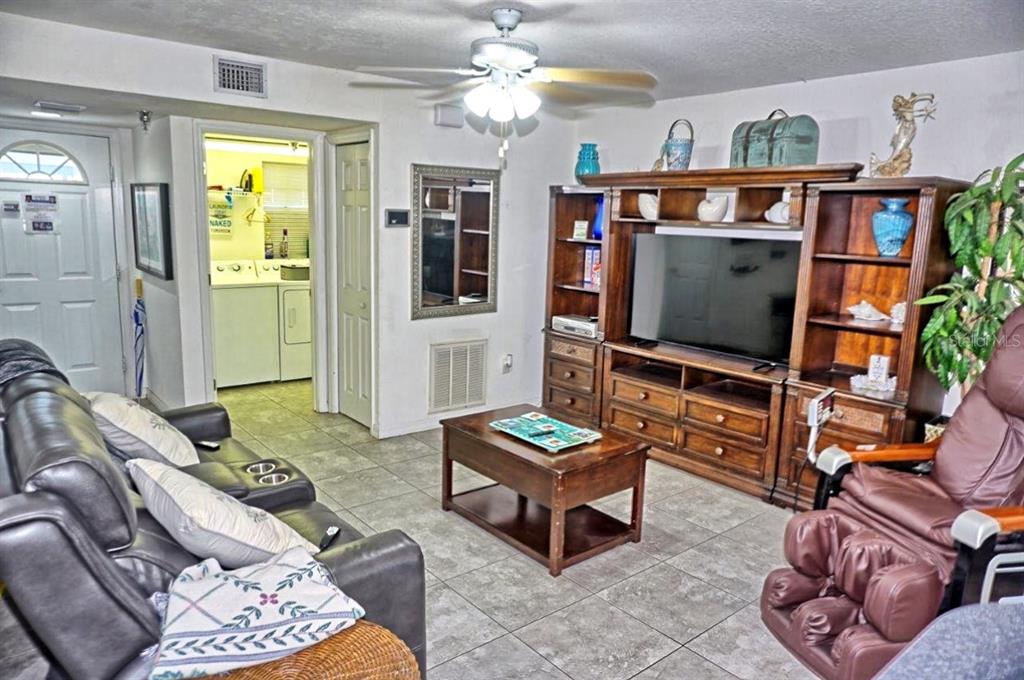 A living room features tile flooring, a large wooden entertainment center, and a leather recliner — 21107 FOUNTAIN VIEW LANE UNIT 5102, LUTZ, FL
