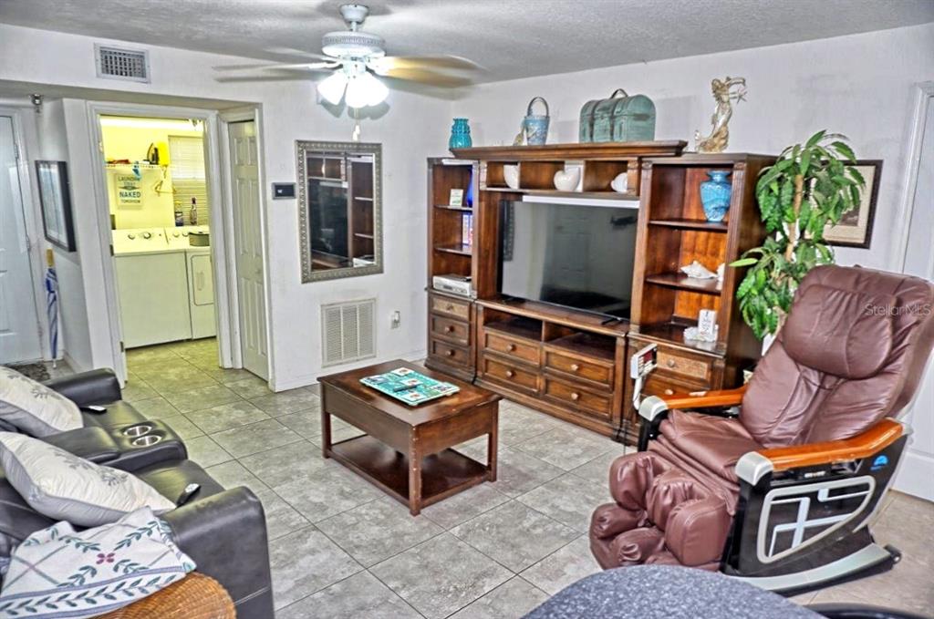 A living room features tile floors, a wooden entertainment center, and a brown massage chair — 21107 FOUNTAIN VIEW LANE UNIT 5102, LUTZ, FL