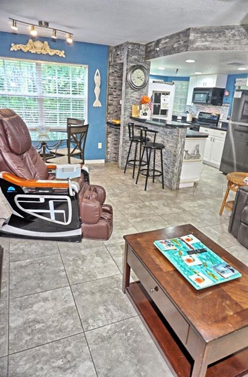 A living room features a massage chair, a coffee table, and a breakfast bar area — 21107 FOUNTAIN VIEW LANE UNIT 5102, LUTZ, FL