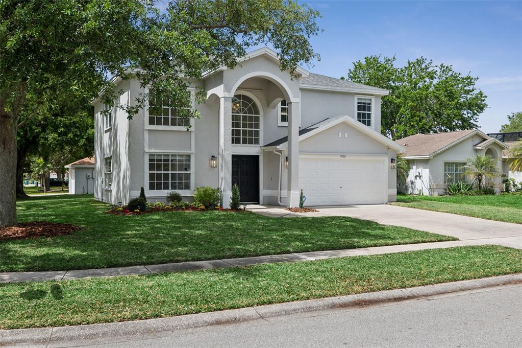 A two-story house with a light gray exterior, arched entryway, and a two-car garage — 7006 BLACKBERRY CT, MELBOURNE, FL