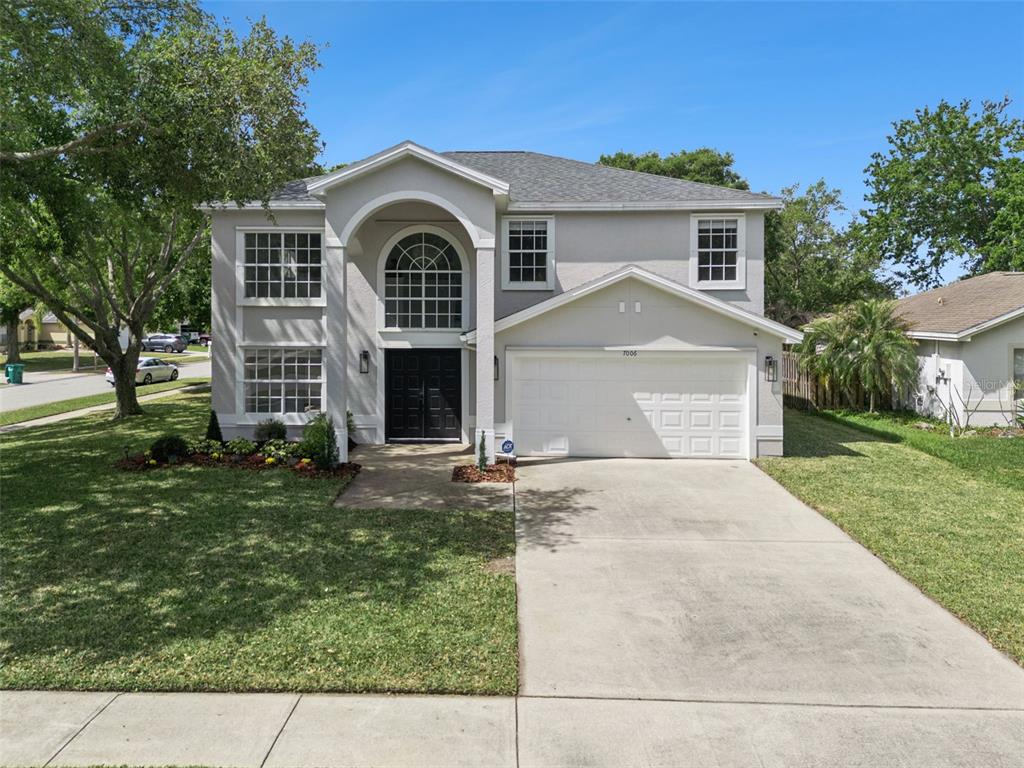 A two-story suburban house features a light gray exterior, a two-car garage, and arched windows — 7006 BLACKBERRY CT, MELBOURNE, FL