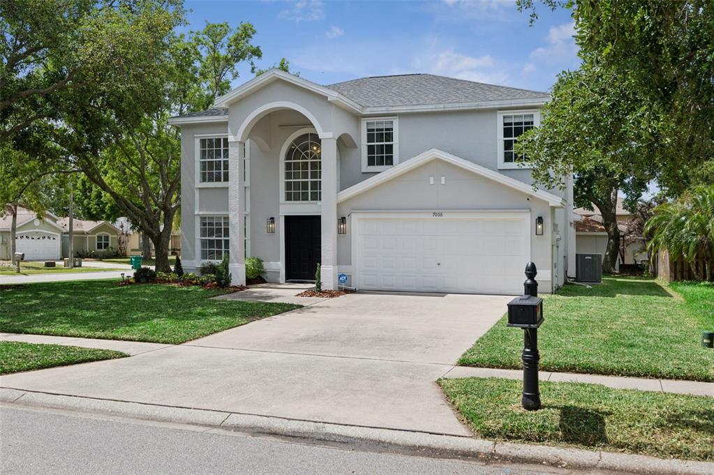 A two-story house with a light gray exterior, a two-car garage, and a covered entryway — 7006 BLACKBERRY CT, MELBOURNE, FL