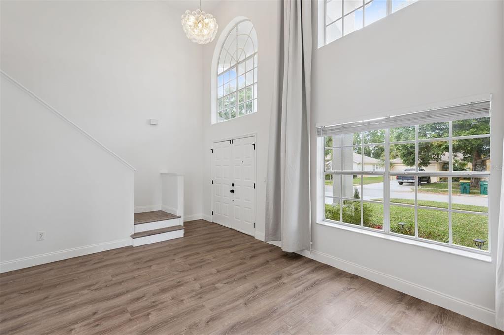 An entryway with wood-look flooring, a high ceiling, a staircase, and a large arched window — 7006 BLACKBERRY CT, MELBOURNE, FL