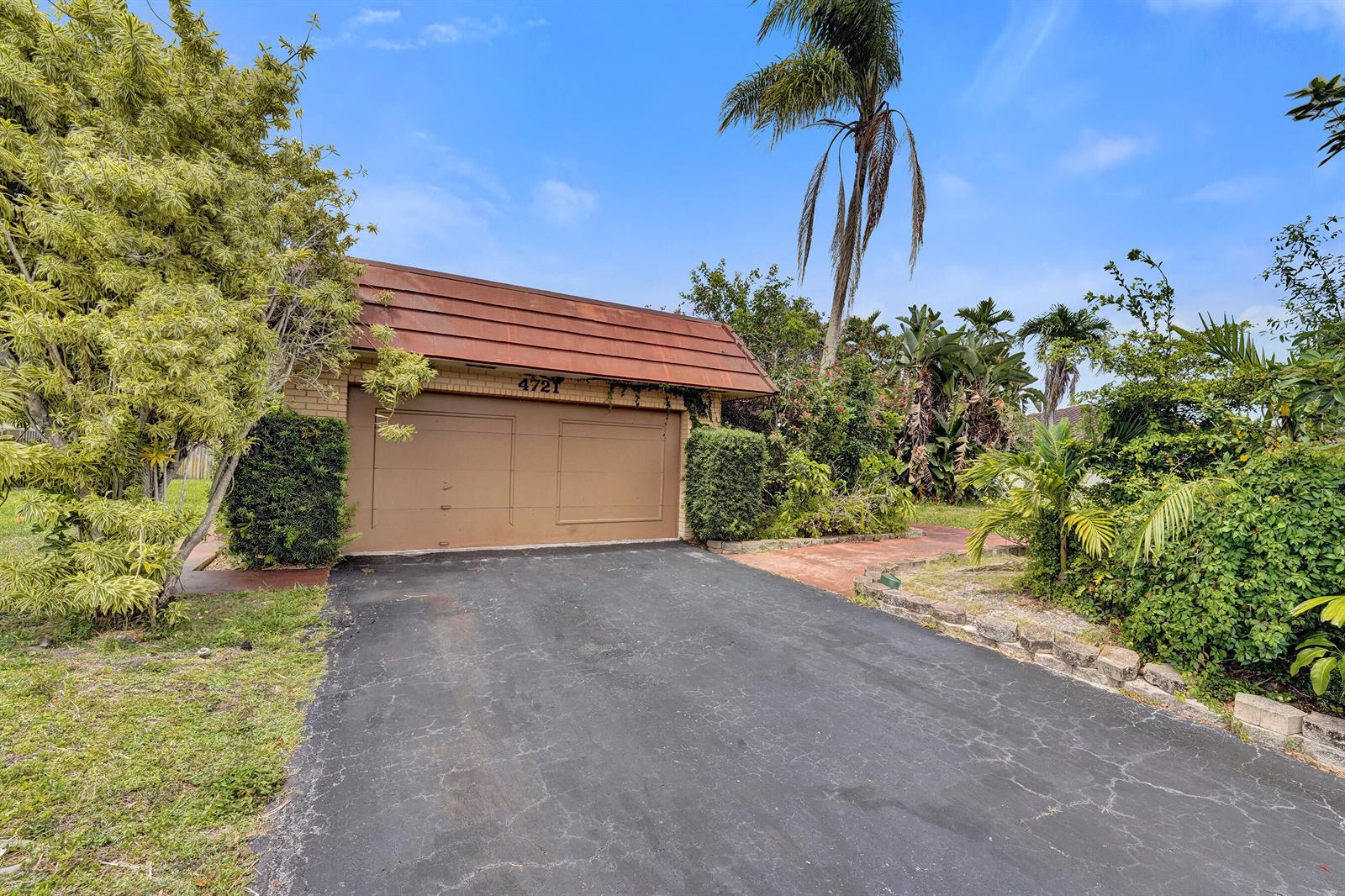 A two-car garage with a brown door and a sloped roof sits at the driveway — 4721 Sarazen Drive, Hollywood FL 33021, HOLLYWOOD, FL