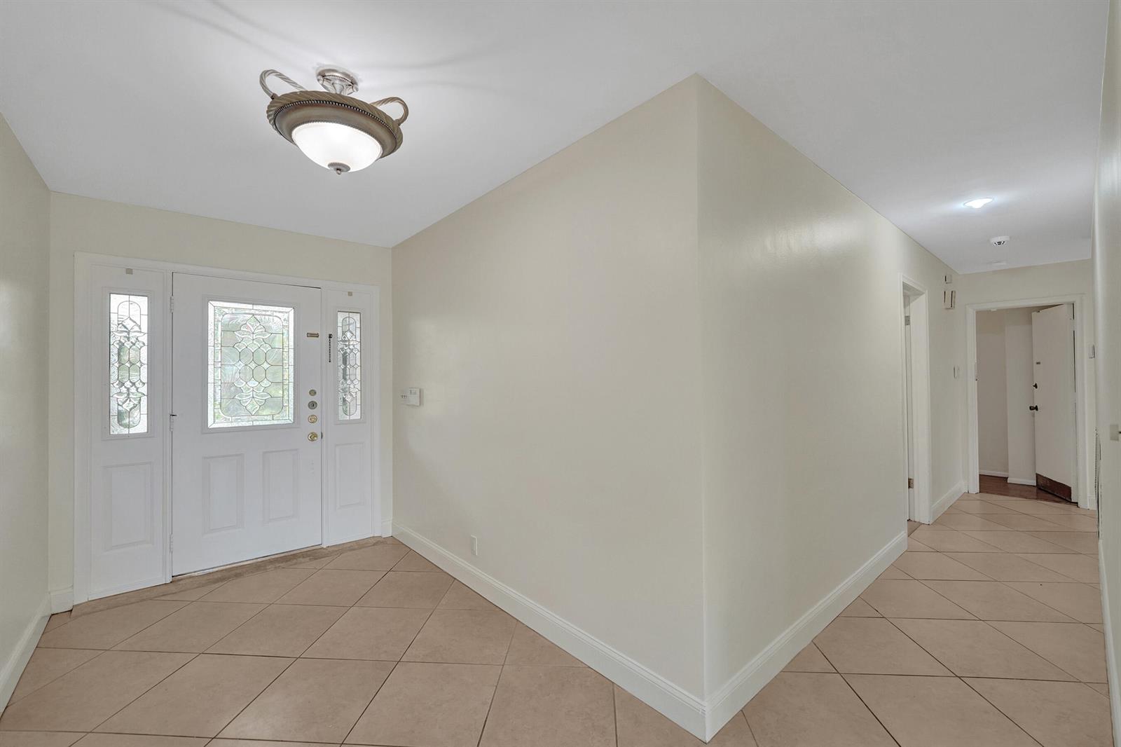 An entryway features a white front door with glass panels, tile flooring, and a ceiling light — 4721 Sarazen Drive, Hollywood FL 33021, HOLLYWOOD, FL