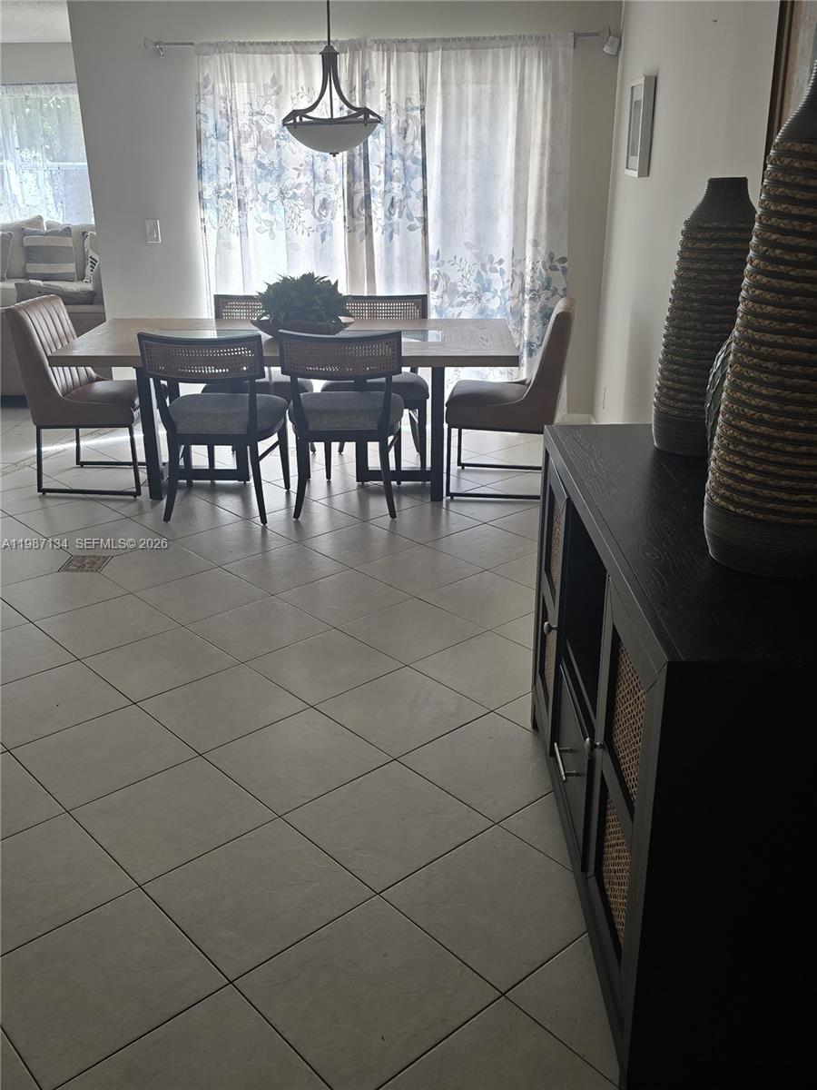 A dining area features a wooden table, six chairs, and a dark cabinet nearby — 6690 NW 38th Dr, Lauderhill FL 33319, LAUDERHILL, FL