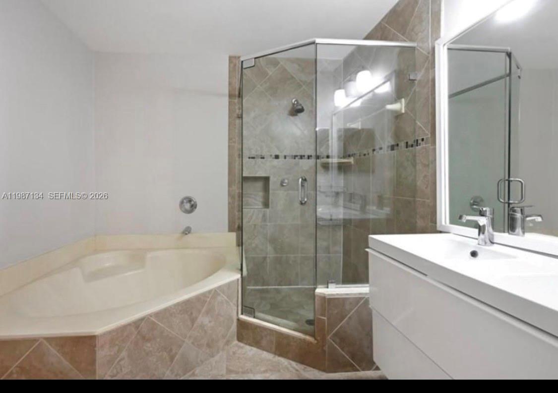 A bathroom features a corner soaking tub, a glass-enclosed shower, and a white vanity — 6690 NW 38th Dr, Lauderhill FL 33319, LAUDERHILL, FL