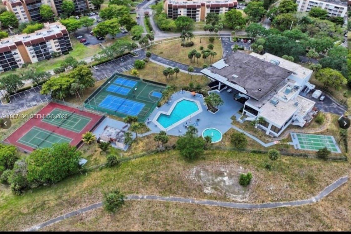 An aerial view of a community clubhouse featuring a swimming pool, tennis courts, and parking — 6690 NW 38th Dr, Lauderhill FL 33319, LAUDERHILL, FL