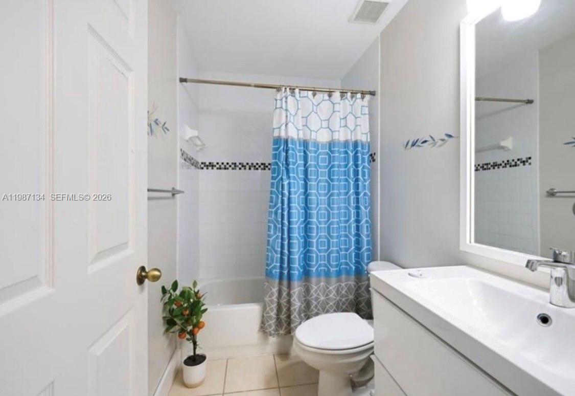 A bathroom features a white vanity, a toilet, and a bathtub with a patterned curtain — 6690 NW 38th Dr, Lauderhill FL 33319, LAUDERHILL, FL