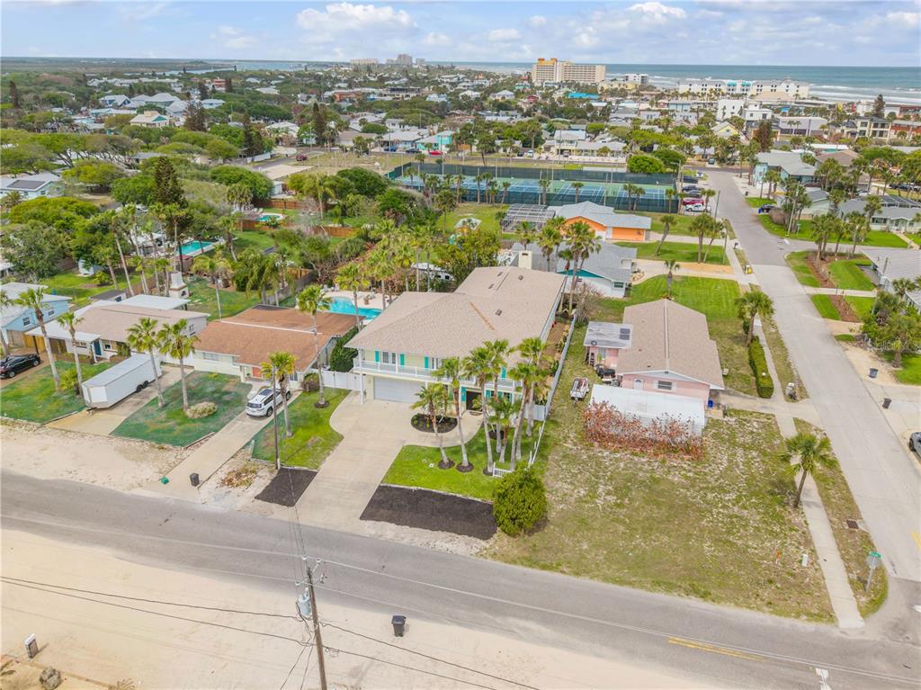 An aerial view shows a two-story house with a pool and palm trees near the coast — 708 OCEAN AVENUE, NEW SMYRNA BEACH, FL