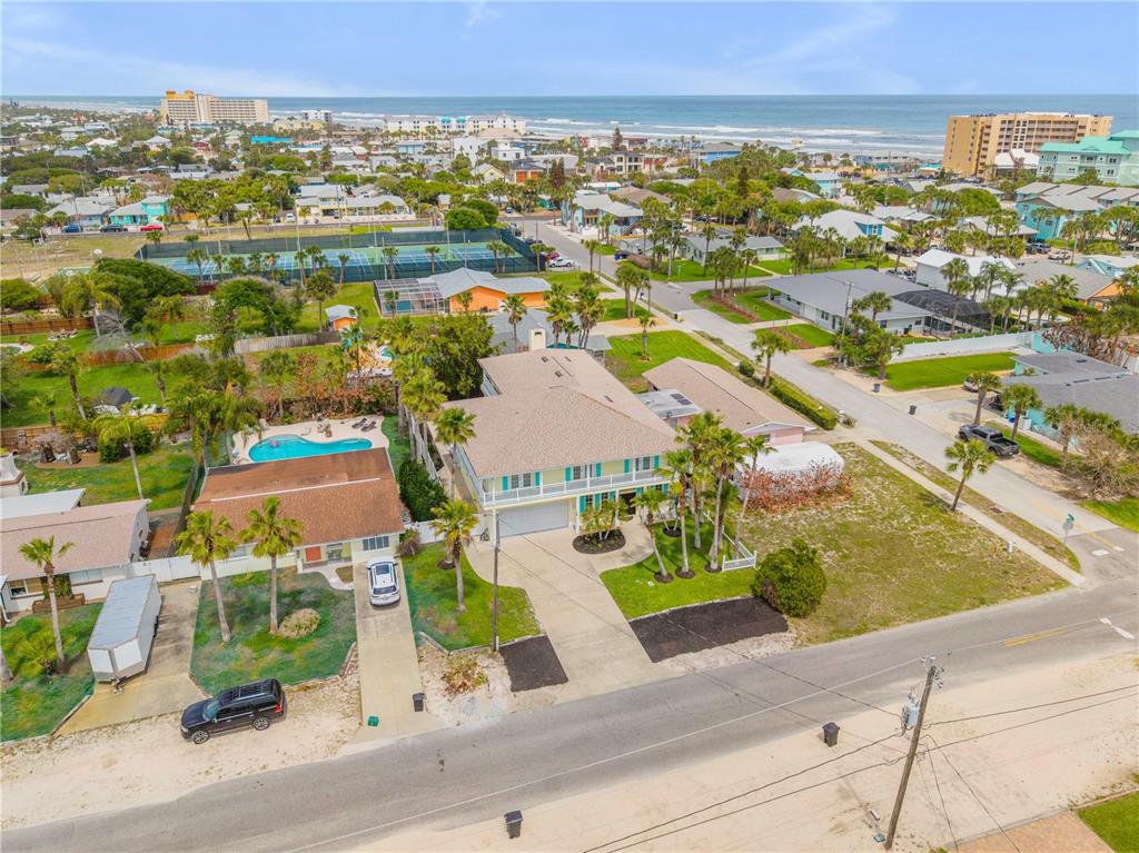 An aerial view shows a two-story house with a pool, driveway, and surrounding coastal neighborhood — 708 OCEAN AVENUE, NEW SMYRNA BEACH, FL