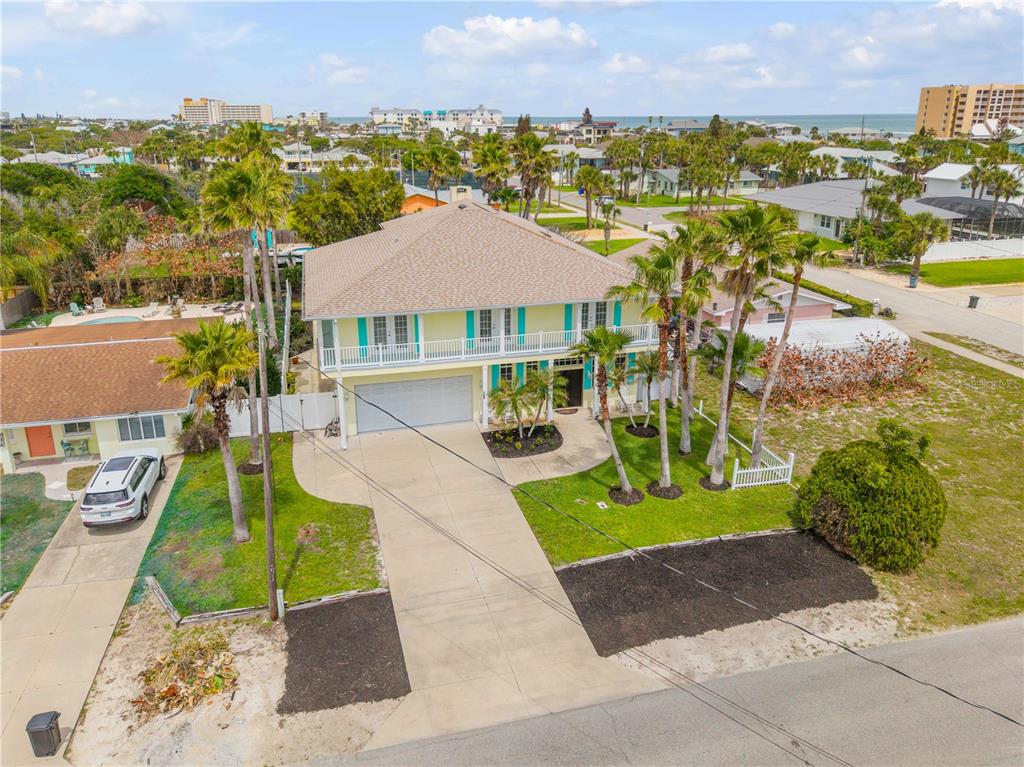An aerial view of a two-story yellow house with a white balcony and driveway — 708 OCEAN AVENUE, NEW SMYRNA BEACH, FL