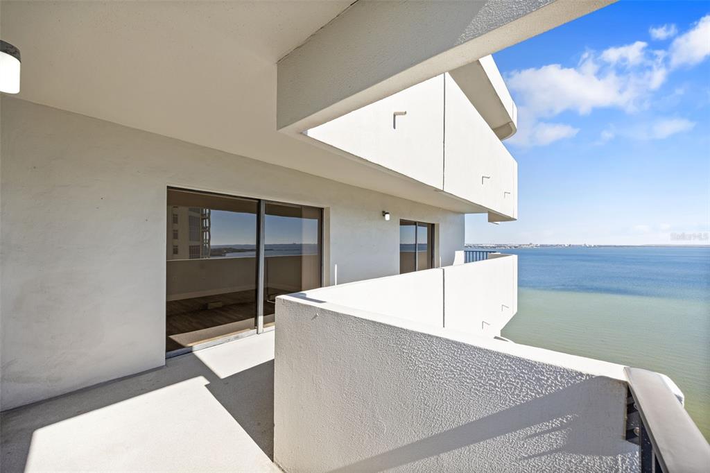 A balcony with white concrete walls overlooks a large body of water — 4141 BAYSHORE BOULEVARD UNIT 1702, TAMPA, FL